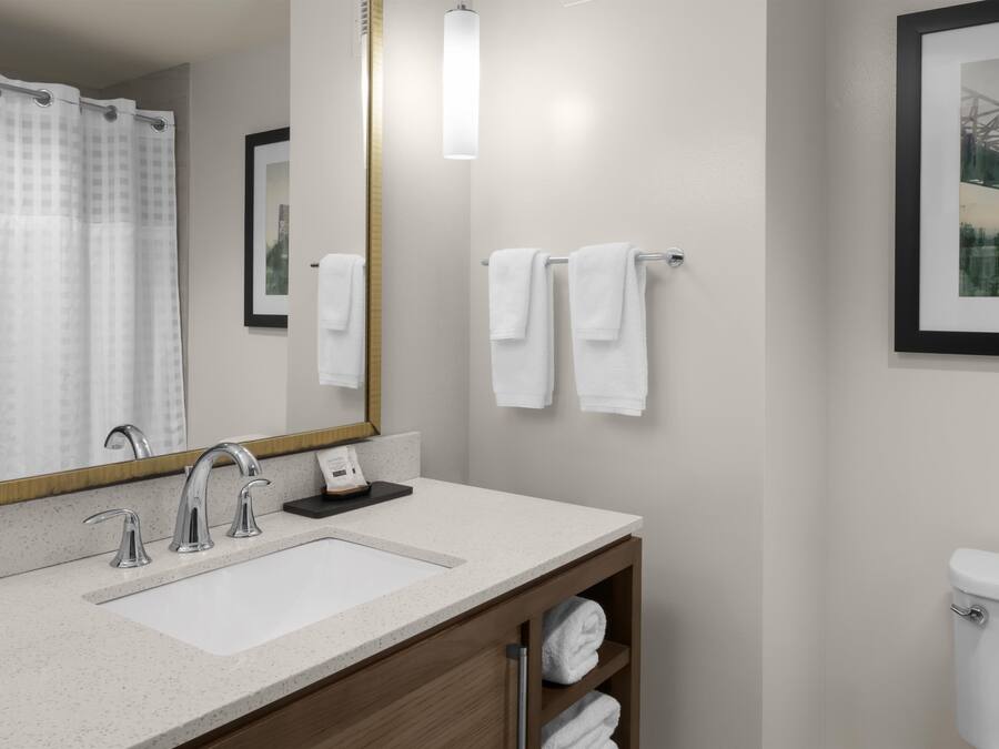 A bathroom with a white sink, a mirror, a towel rack, and a toilet.