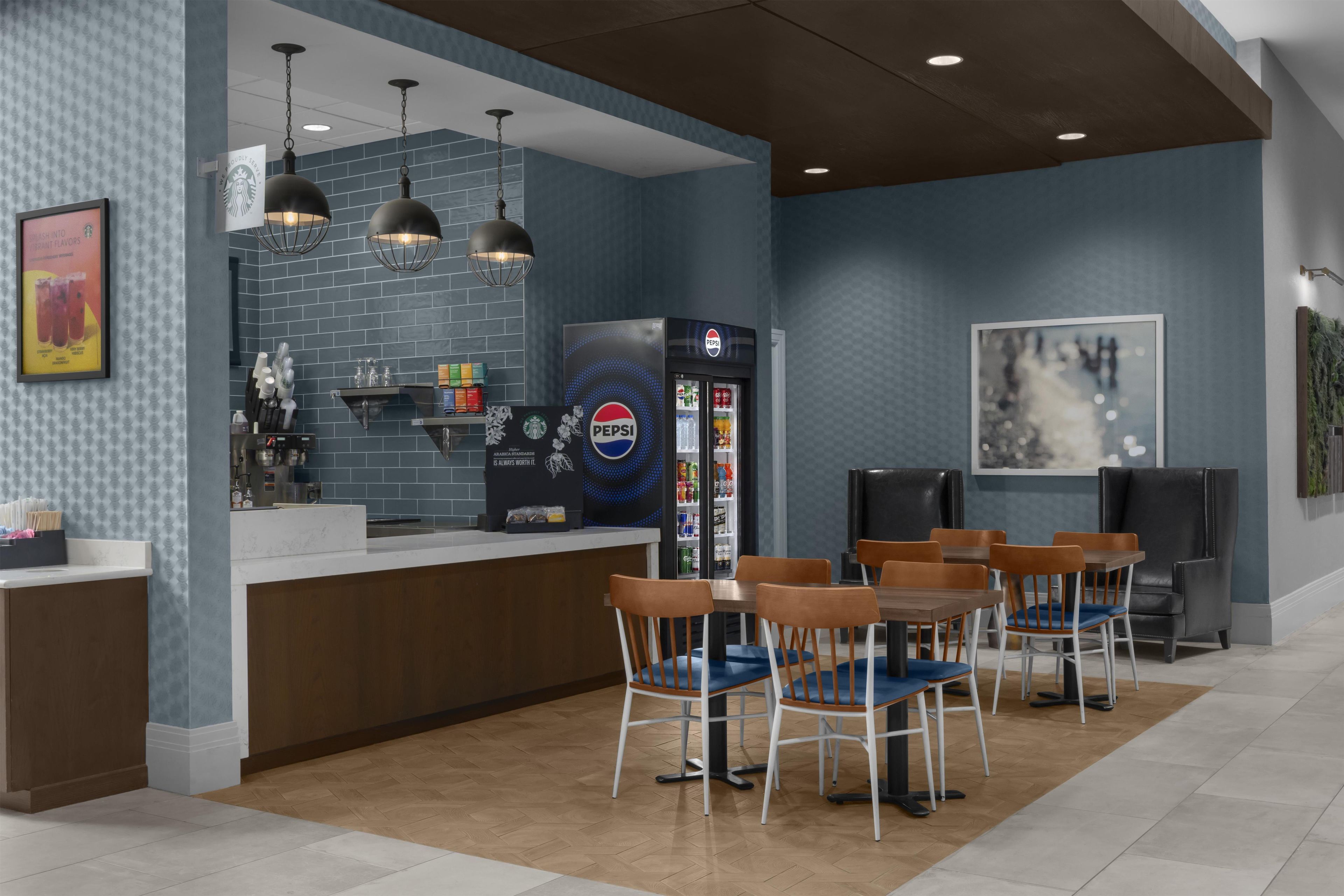 A modern cafe interior with a counter, seating area, and a refrigerator.