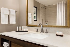 Een hotelbadkamer met een grote spiegel, twee wasbakken en een douche.
