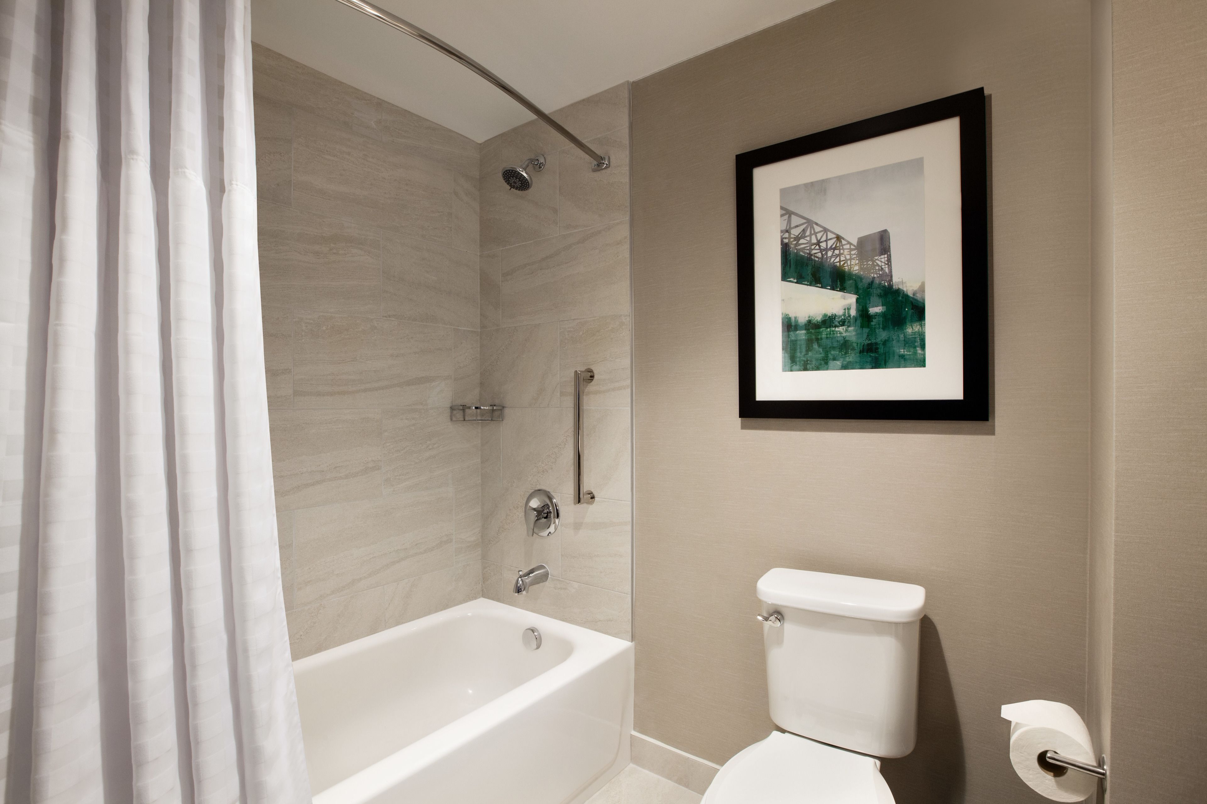 Une salle de bain moderne avec une baignoire, des toilettes et un tableau encadré au mur.