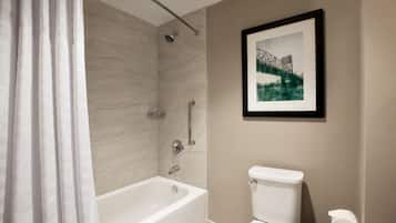 A modern bathroom with a bathtub, toilet, and a framed picture on the wall.