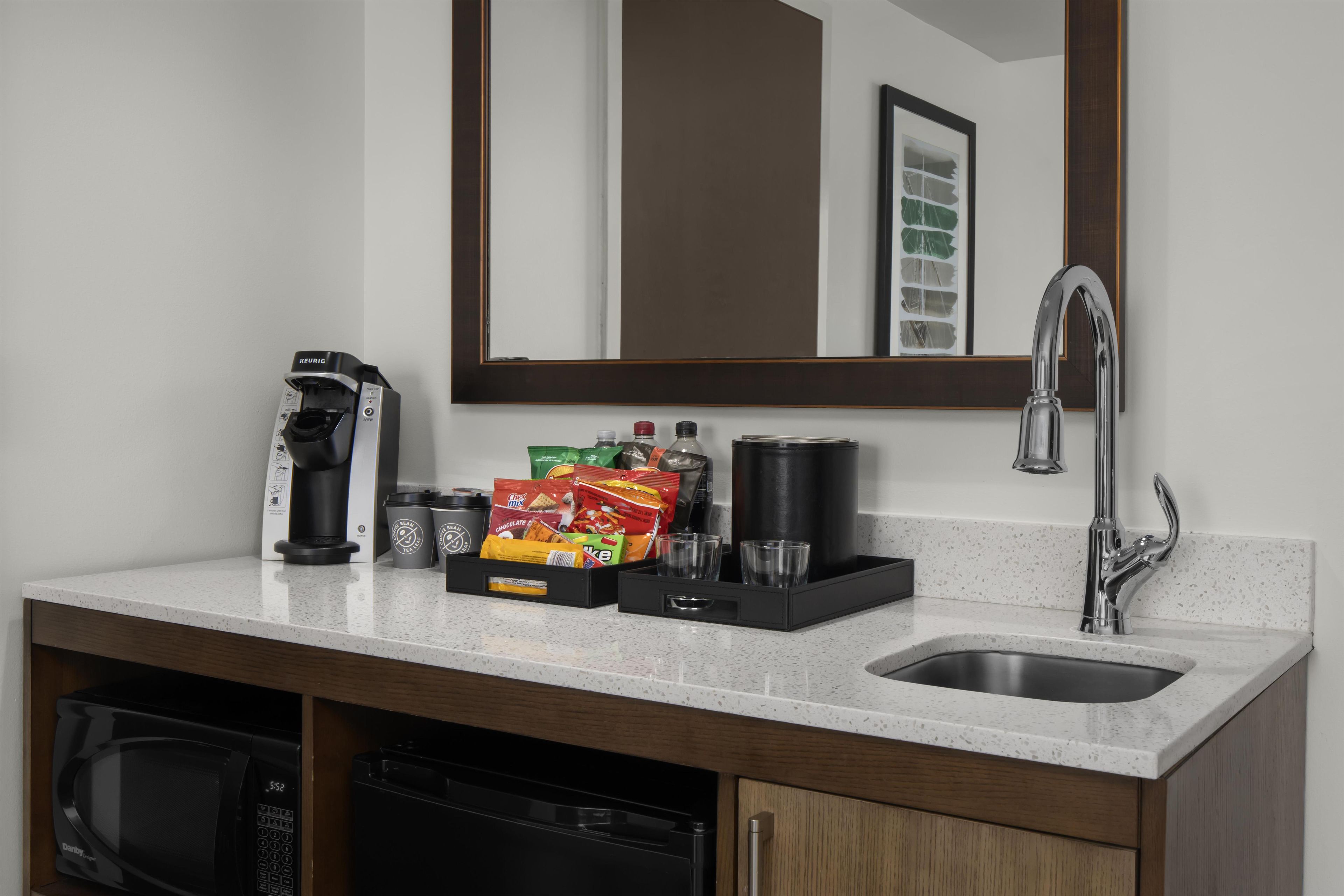 A kitchenette with a coffee maker, tea bags, a coffee grinder, and a microwave.