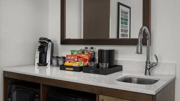 Una kitchenette equipada con cafetera, bolsitas de té, molinillo de café y microondas.
