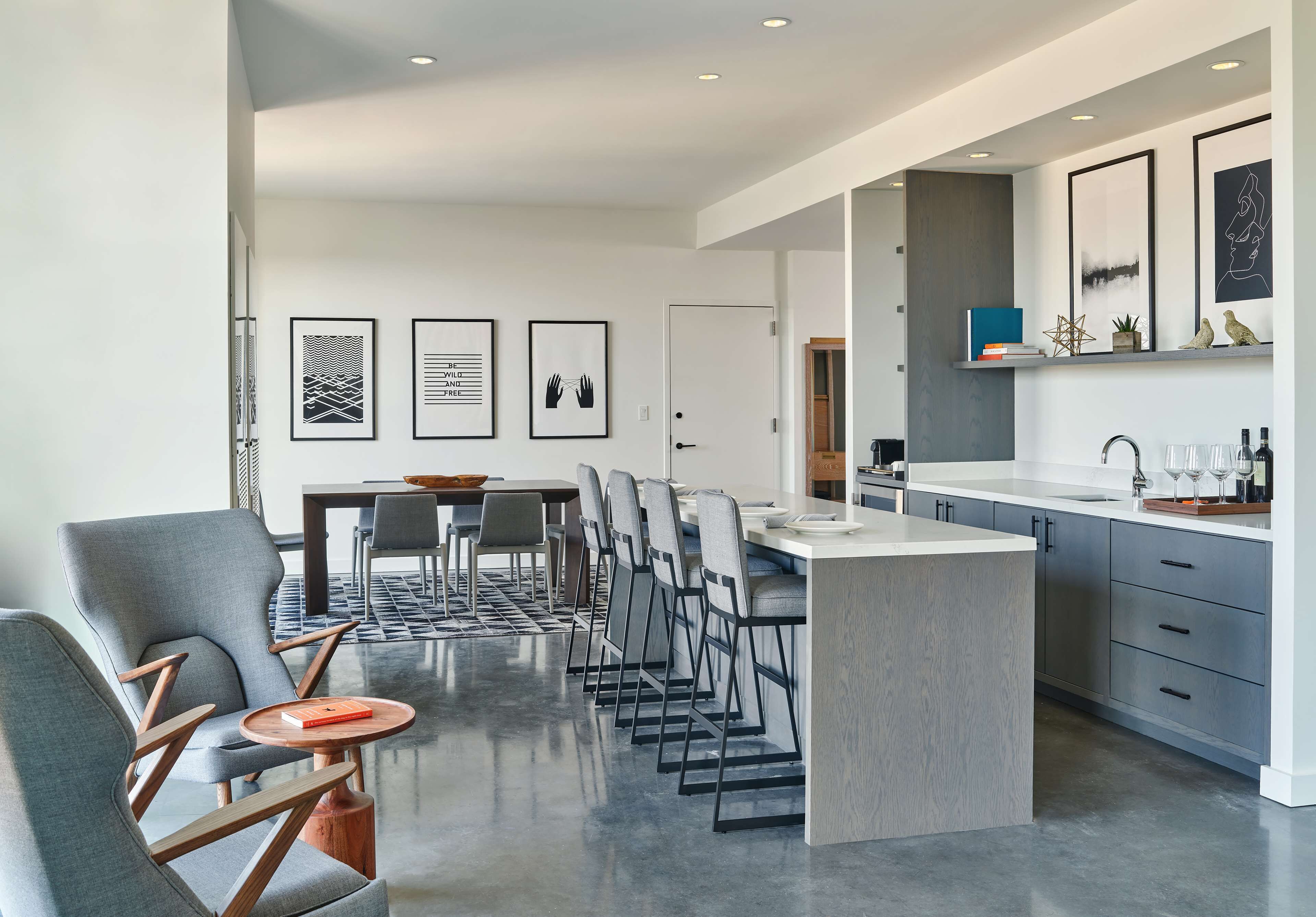 Una cocina moderna con una isla central, taburetes de bar y un comedor con mesa y sillas.