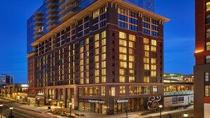 Un hôtel à plusieurs étages doté d’une façade en verre, de nombreux balcons et de fenêtres illuminées.