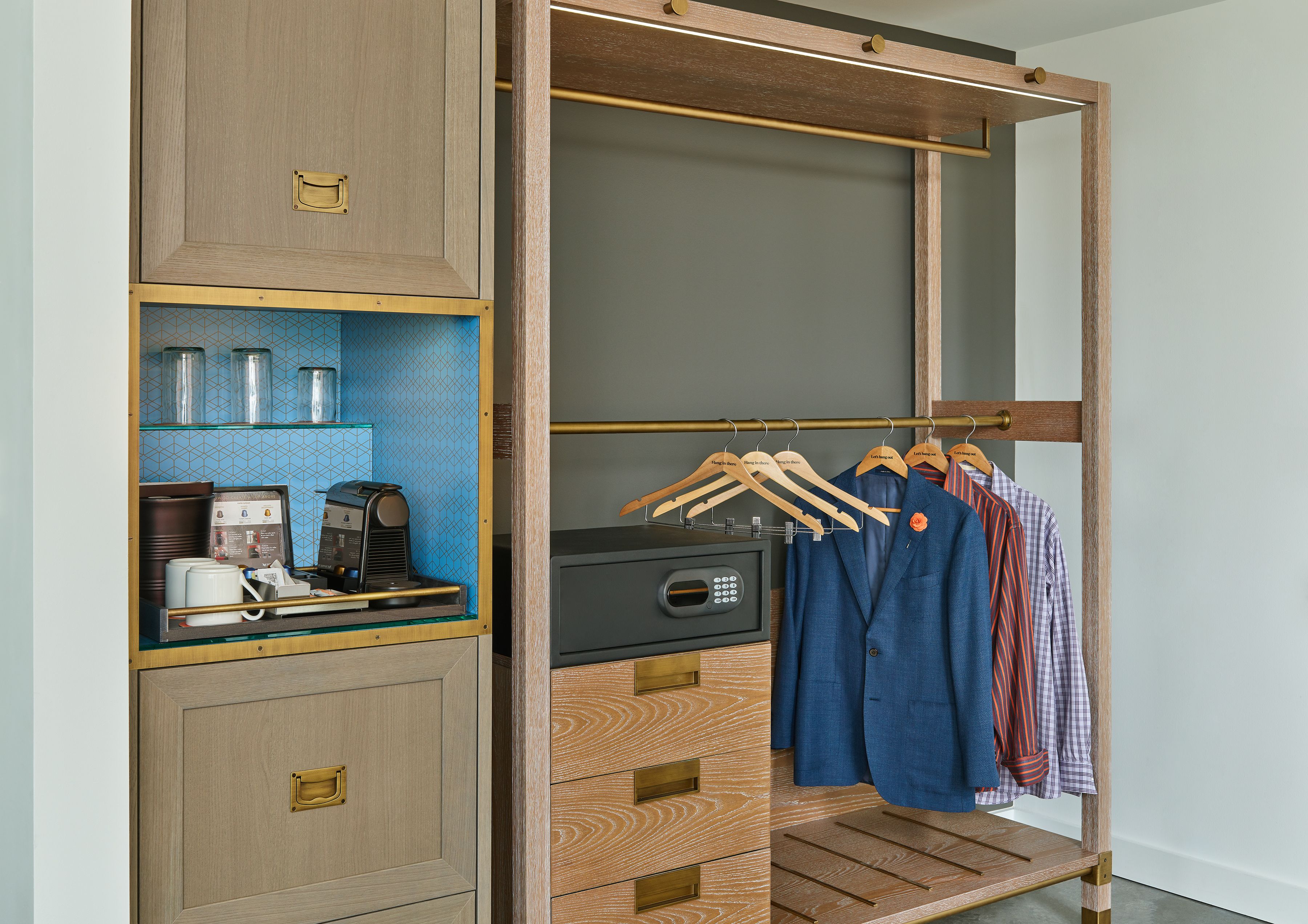 Um closet amplo com um guarda-roupa de madeira, uma cafeteira e cabides com roupas.
