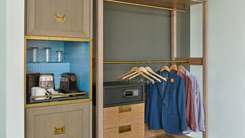 Um closet amplo com um guarda-roupa de madeira, uma cafeteira e cabides com roupas.