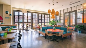 Un café spacieux avec de grandes fenêtres, des sièges confortables et un décor moderne.