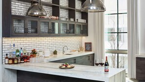 Une cuisine dotée d’un îlot en marbre, de meubles avec des portes en verre et de luminaires suspendus.