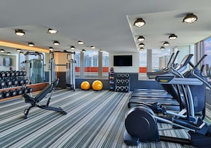 Un gimnasio equipado con cintas de correr, elípticas, mancuernas y pelotas de ejercicio.