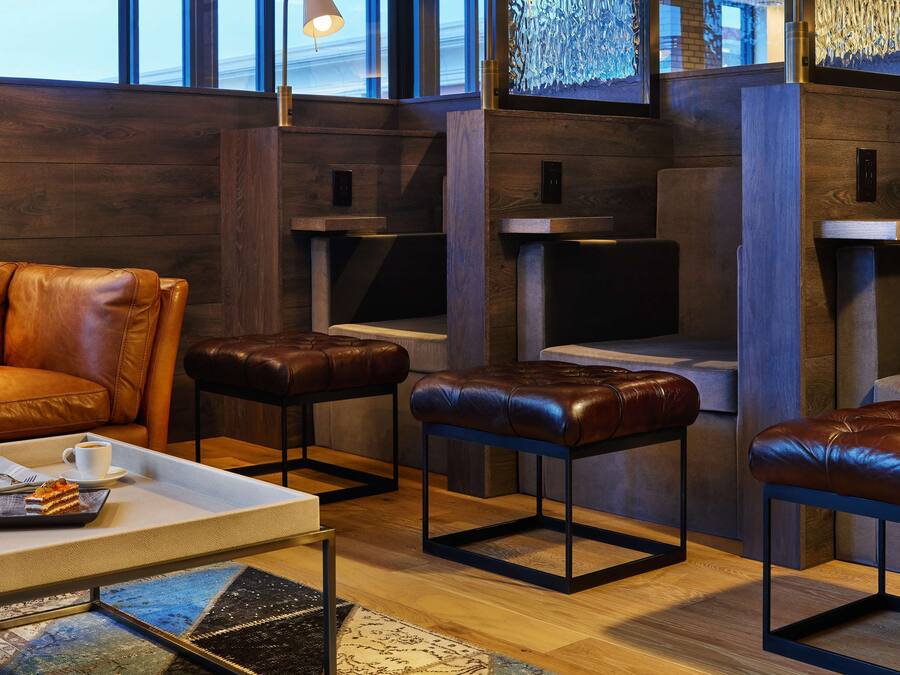A modern lounge area with leather seating, a coffee table with a cake, and a large window with a view.