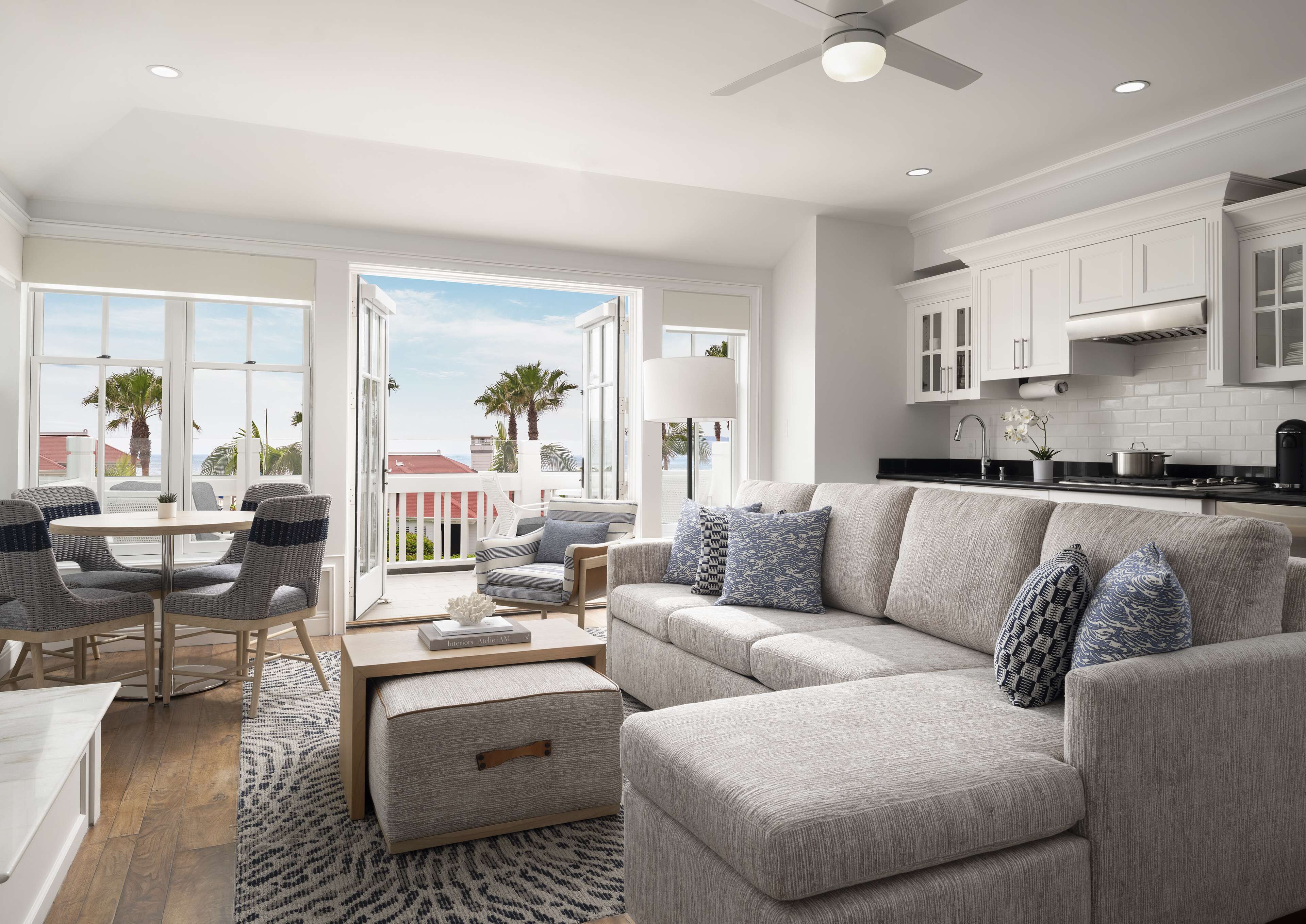 A modern living room with a grey sofa, matching armchairs, a coffee table, and a dining area with a white table and chairs.