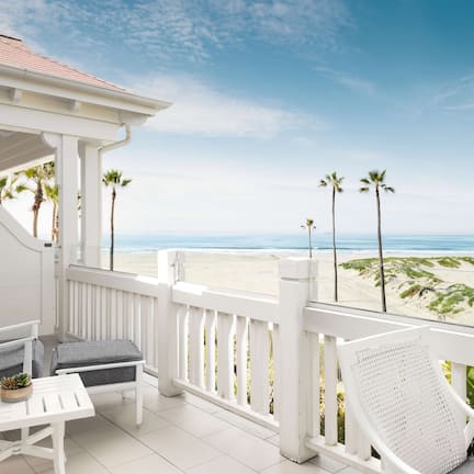 A balcony with white railings, a white table, and two chairs.
