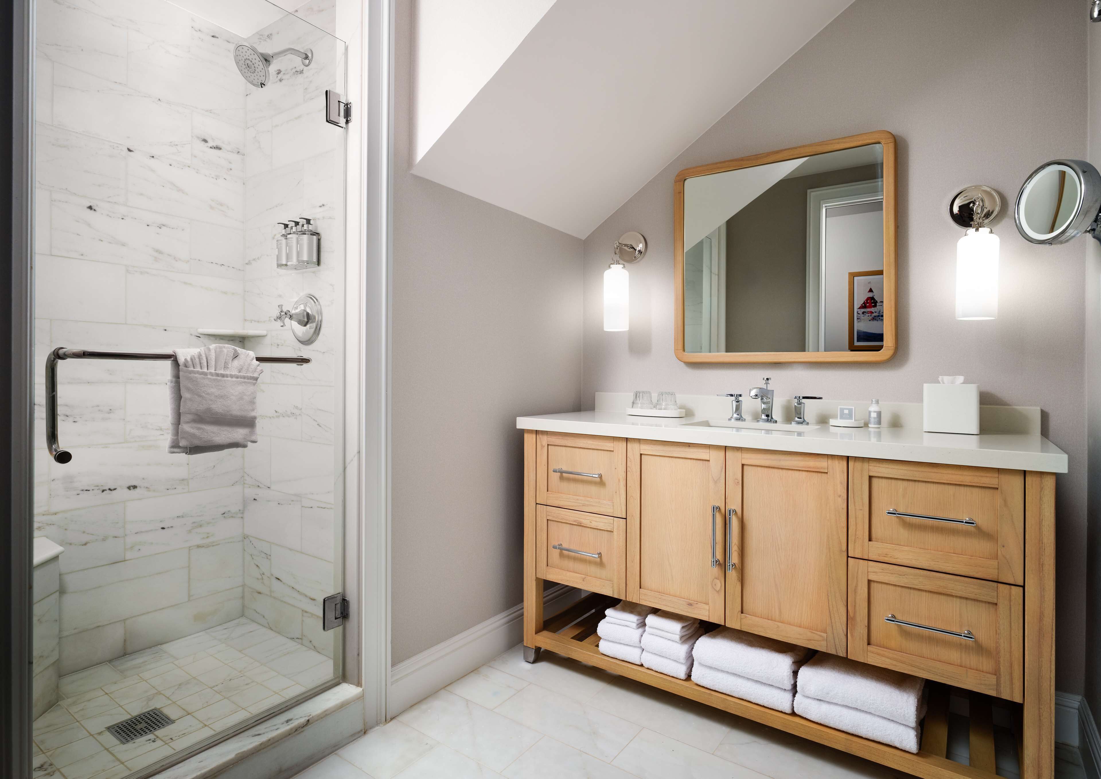 Ein modernes Badezimmer mit Glasdusche, Holzwaschtisch und einem großen Spiegel.