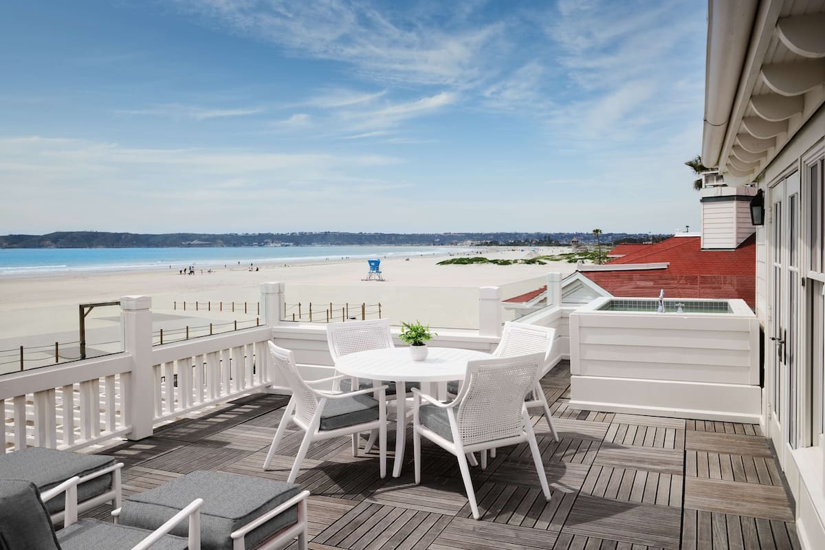 En terrass med ett bord och stolar med utsikt över en strand.