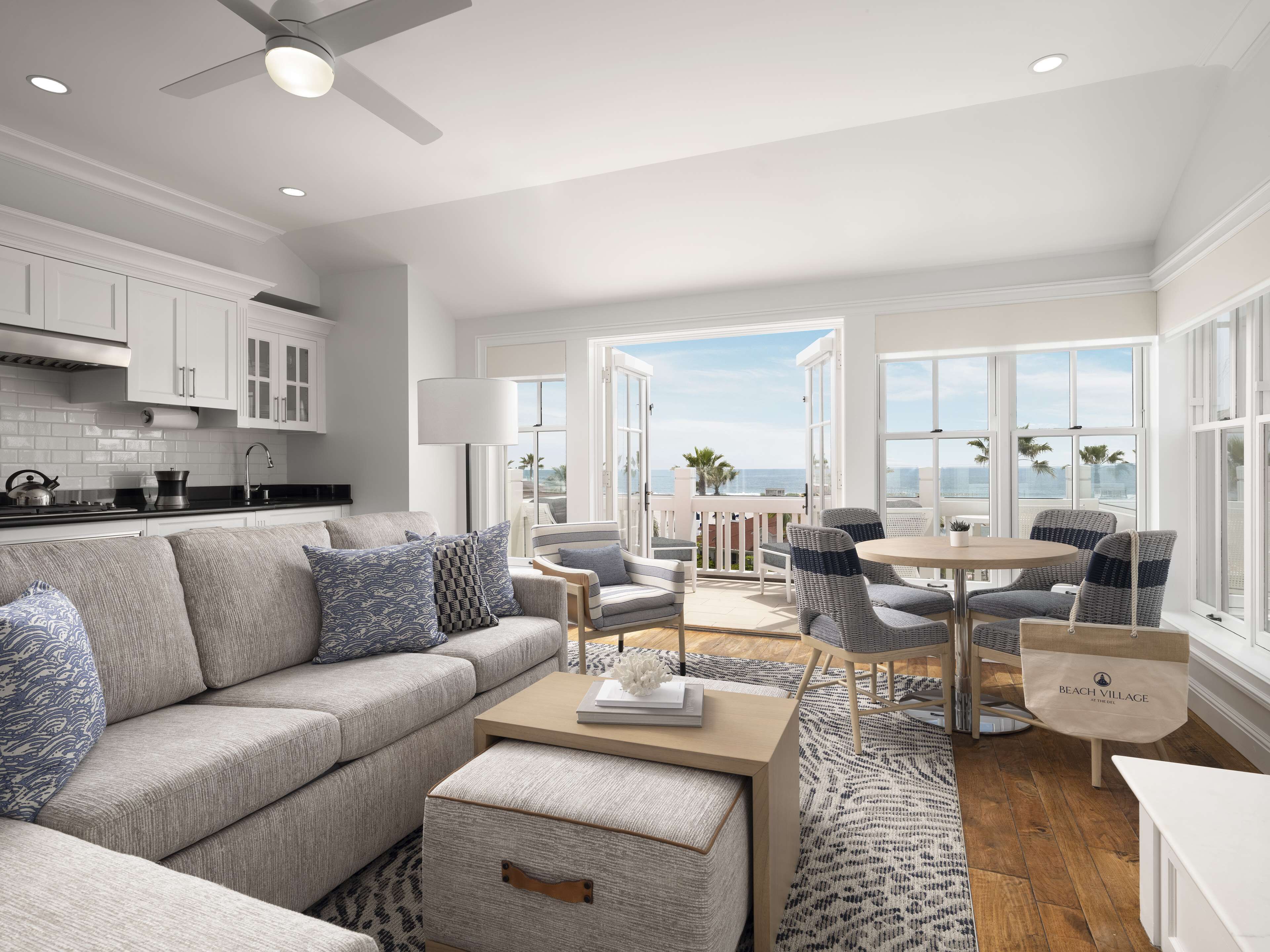 A modern living room with a sofa, chairs, a coffee table, and a view of the ocean.