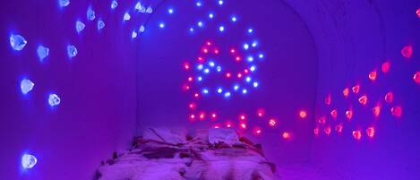 A room with a bed, a stone wall, and decorative lights.
