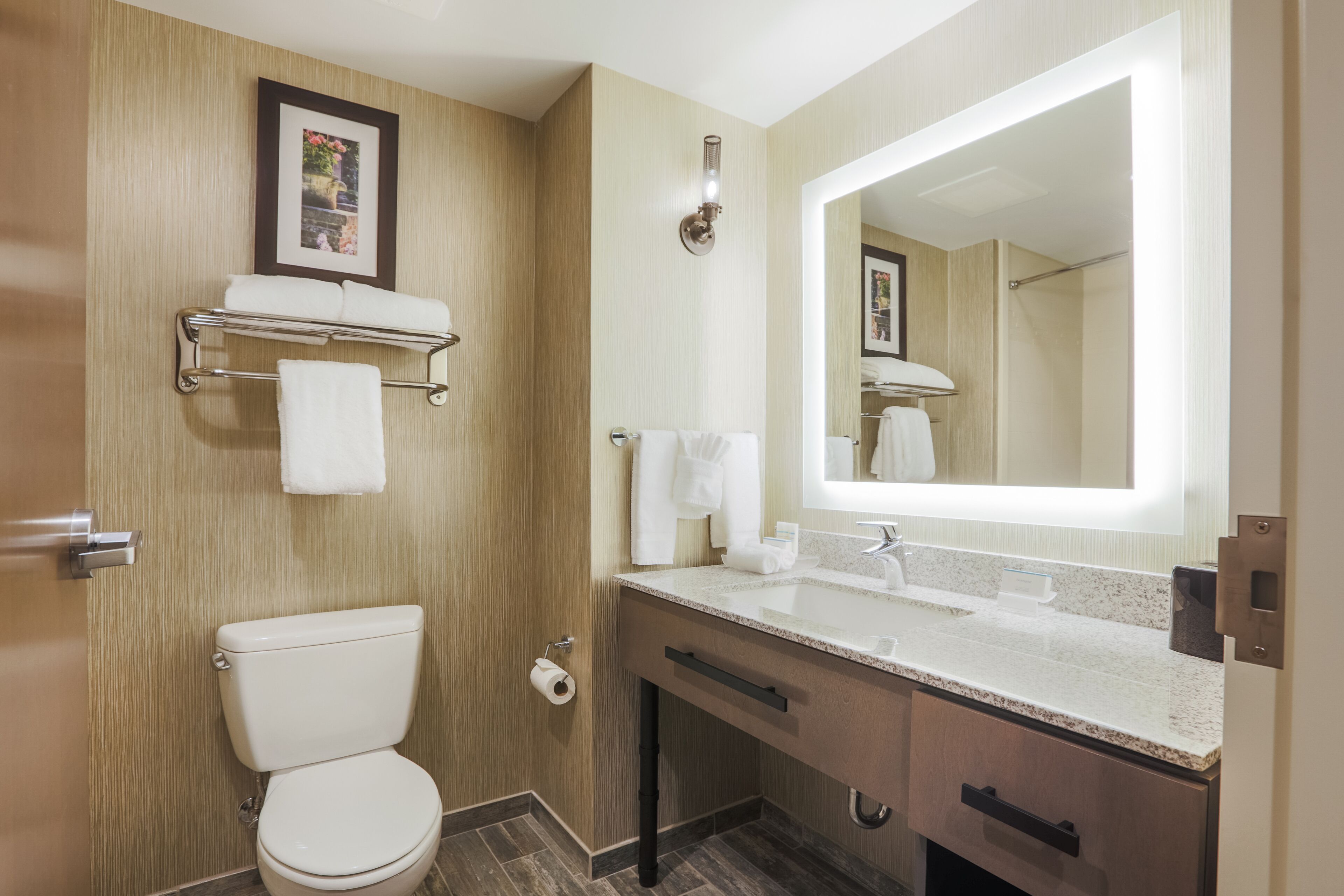 Une salle de bain moderne équipée de toilettes, d’un lavabo, d’un meuble-lavabo et d’un grand miroir.