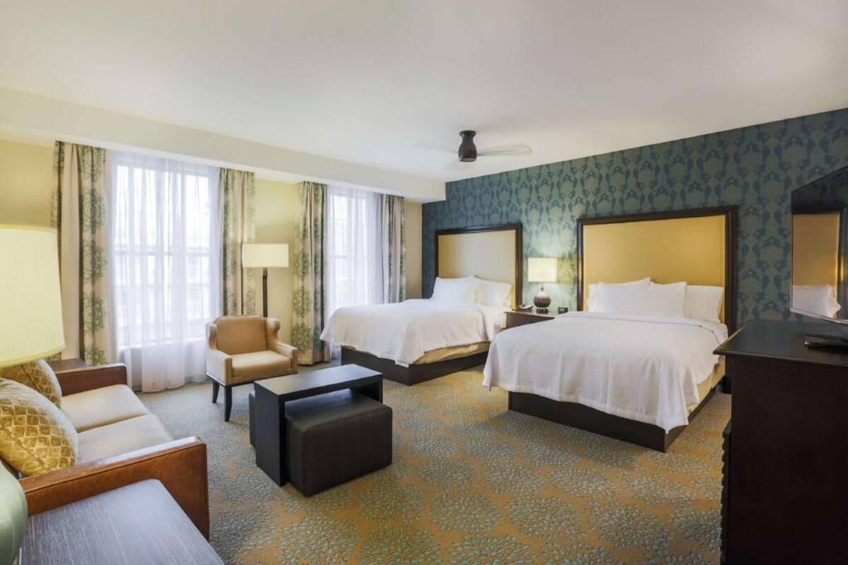 Une chambre d’hôtel avec deux lits, un canapé, une table basse et un bureau.