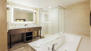 Een moderne badkamer met een grote spiegel, twee wasbakken, een douche met glazen wanden en een losstaand bad.
