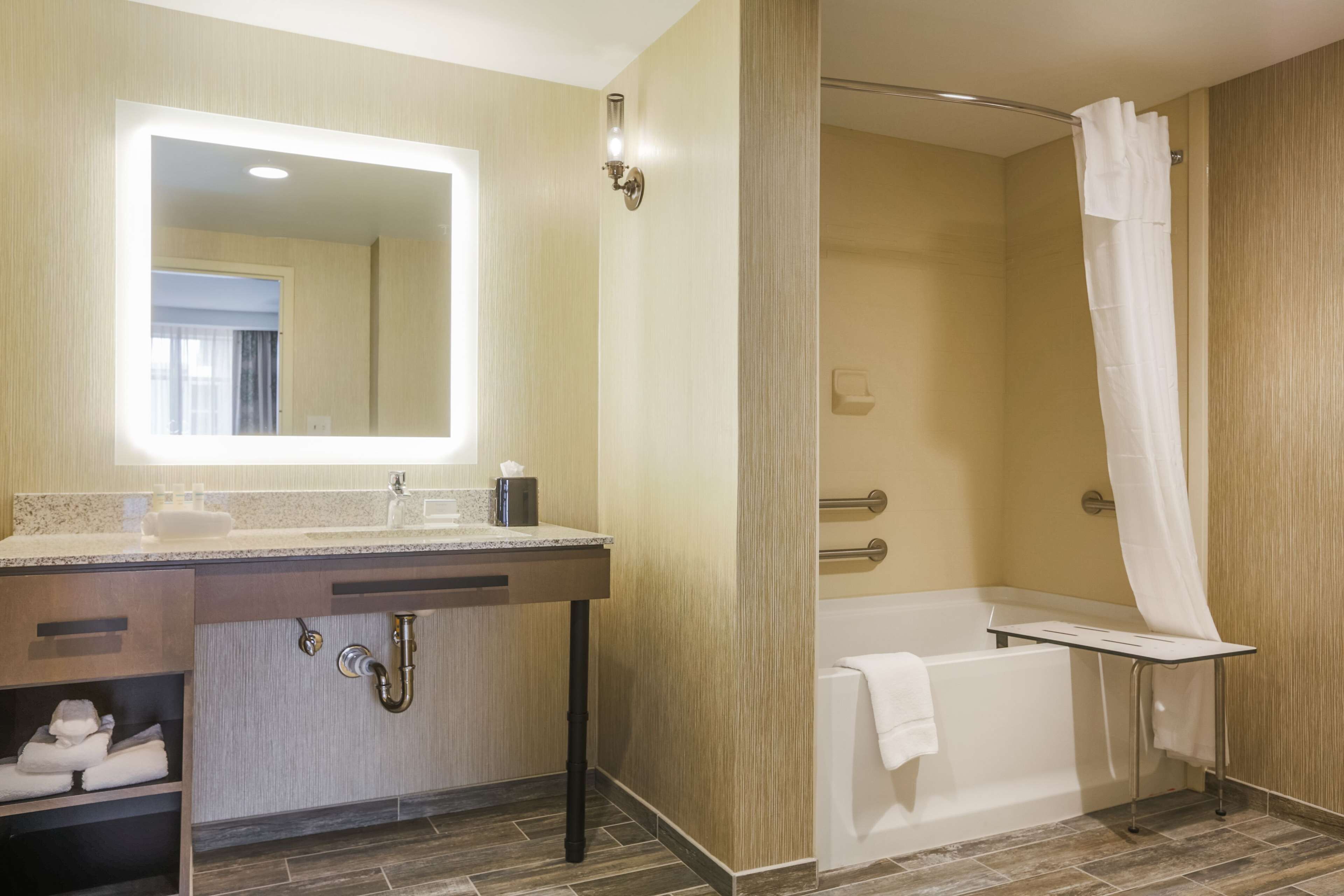 Un baño moderno con tocador, lavamanos, espejo, ducha y bañera.