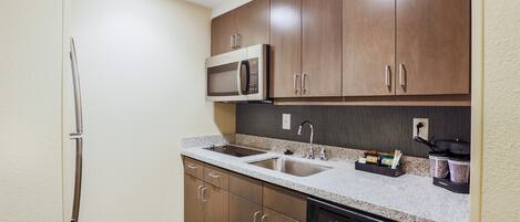 A modern kitchen with stainless steel appliances, a granite countertop, and wooden cabinets.