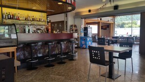 A bar area with stools, a counter with bottles, and a seating area with tables and chairs. - Motel Des Sports (Martigny)