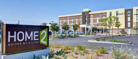 A sign for Home 2 Suites by Hilton with a modern building in the background.