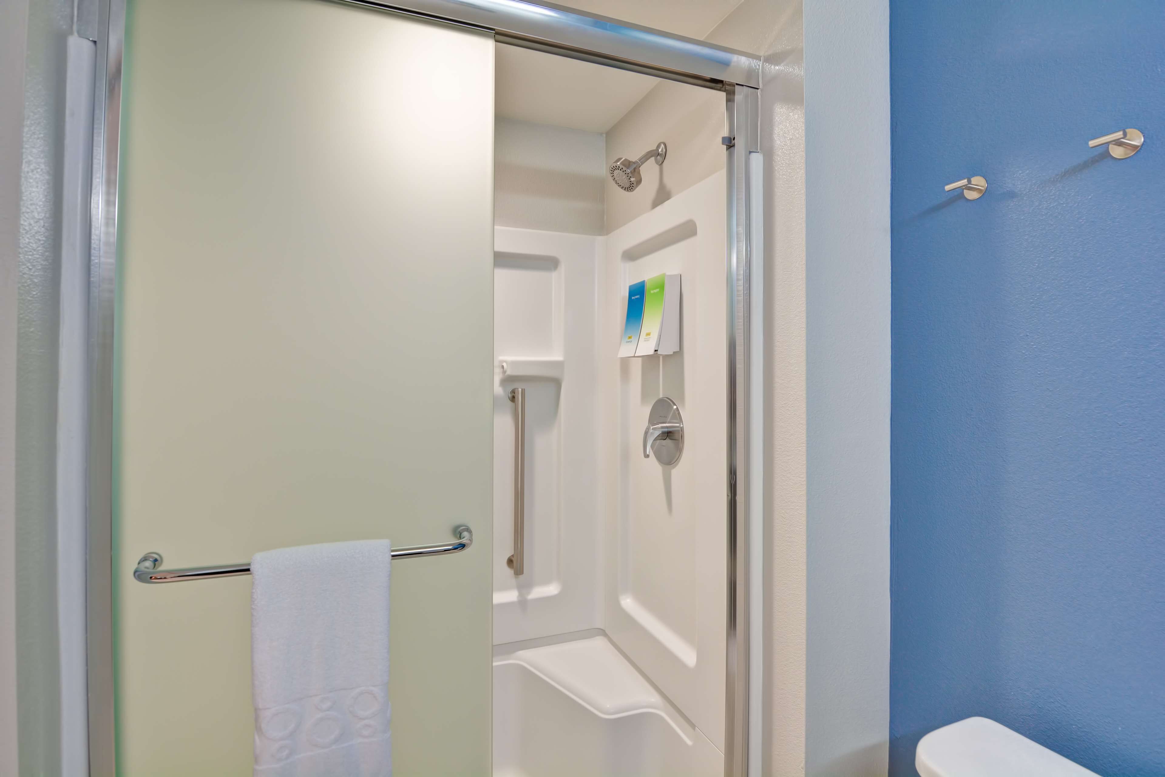 Ein Badezimmer mit Duschkabine aus Glas, einer weißen Toilette und einer blauen Wand.