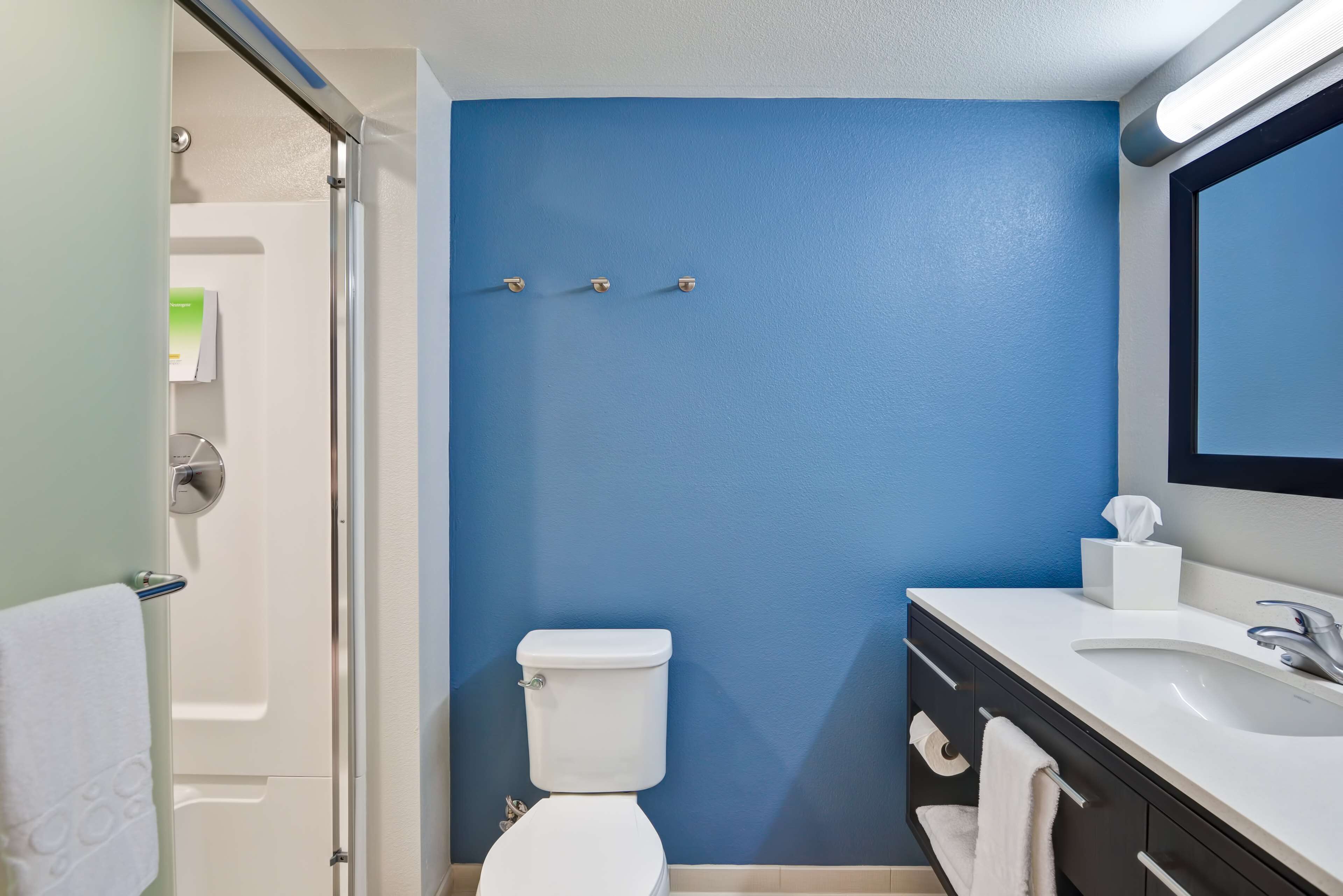 Une salle de bain avec un mur bleu, des toilettes blanches et un meuble-lavabo avec un miroir.