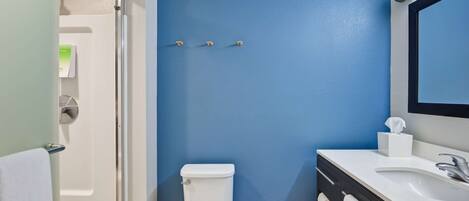 A bathroom with a blue wall, white toilet, and a vanity with a mirror.