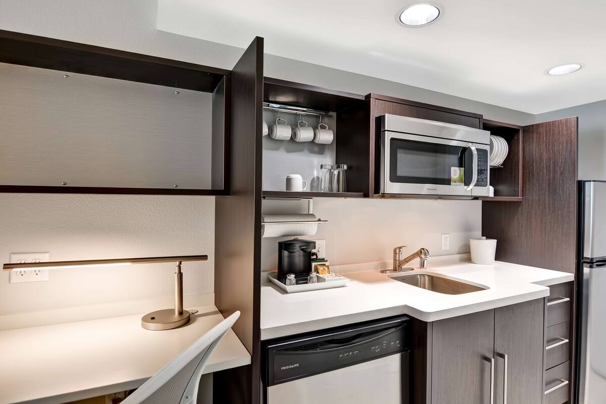 A modern kitchen with a built-in microwave, coffee maker, and dishwasher.