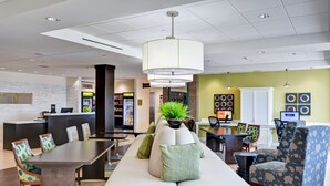 A modern hotel lobby with a reception desk, seating area, and a dining space. - Home2 Suites by Hilton Azusa (Azusa)
