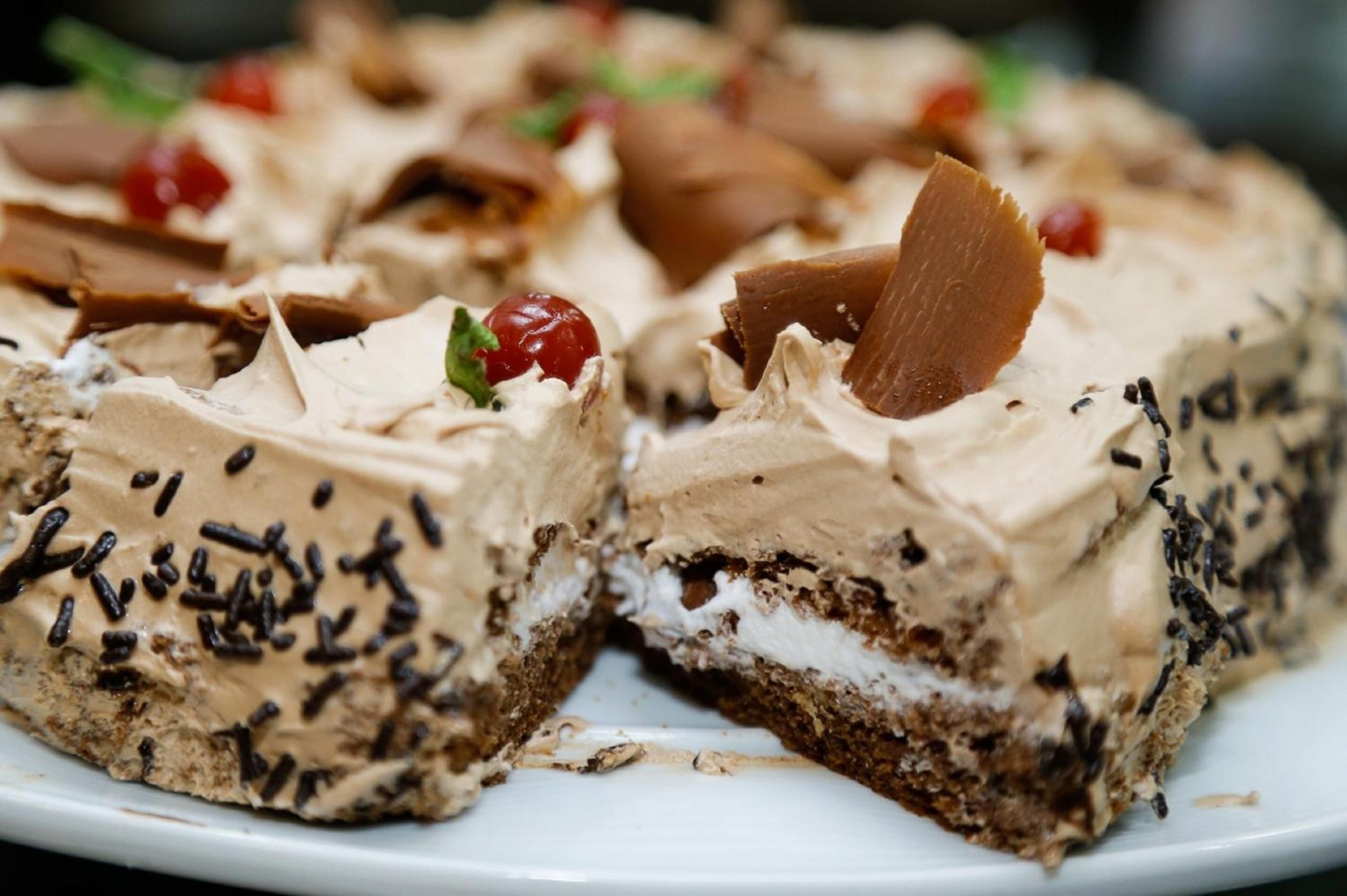 A slice of layered dessert with chocolate and cream.