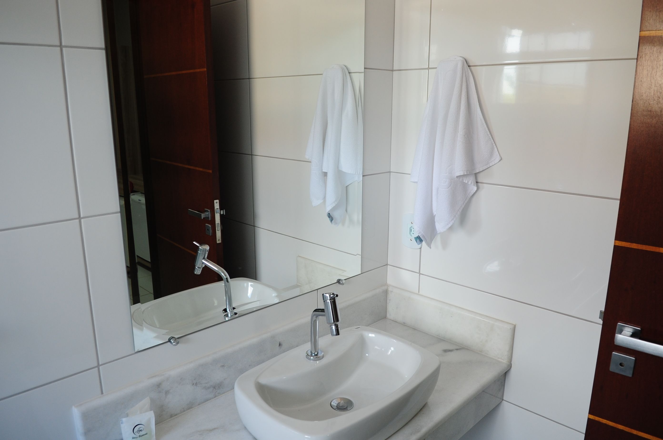 A bathroom with a white sink, a mirror, and two towels hanging on the wall.