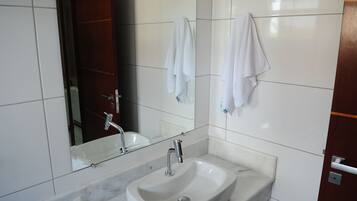 A bathroom with a white sink, a mirror, and two towels hanging on the wall.