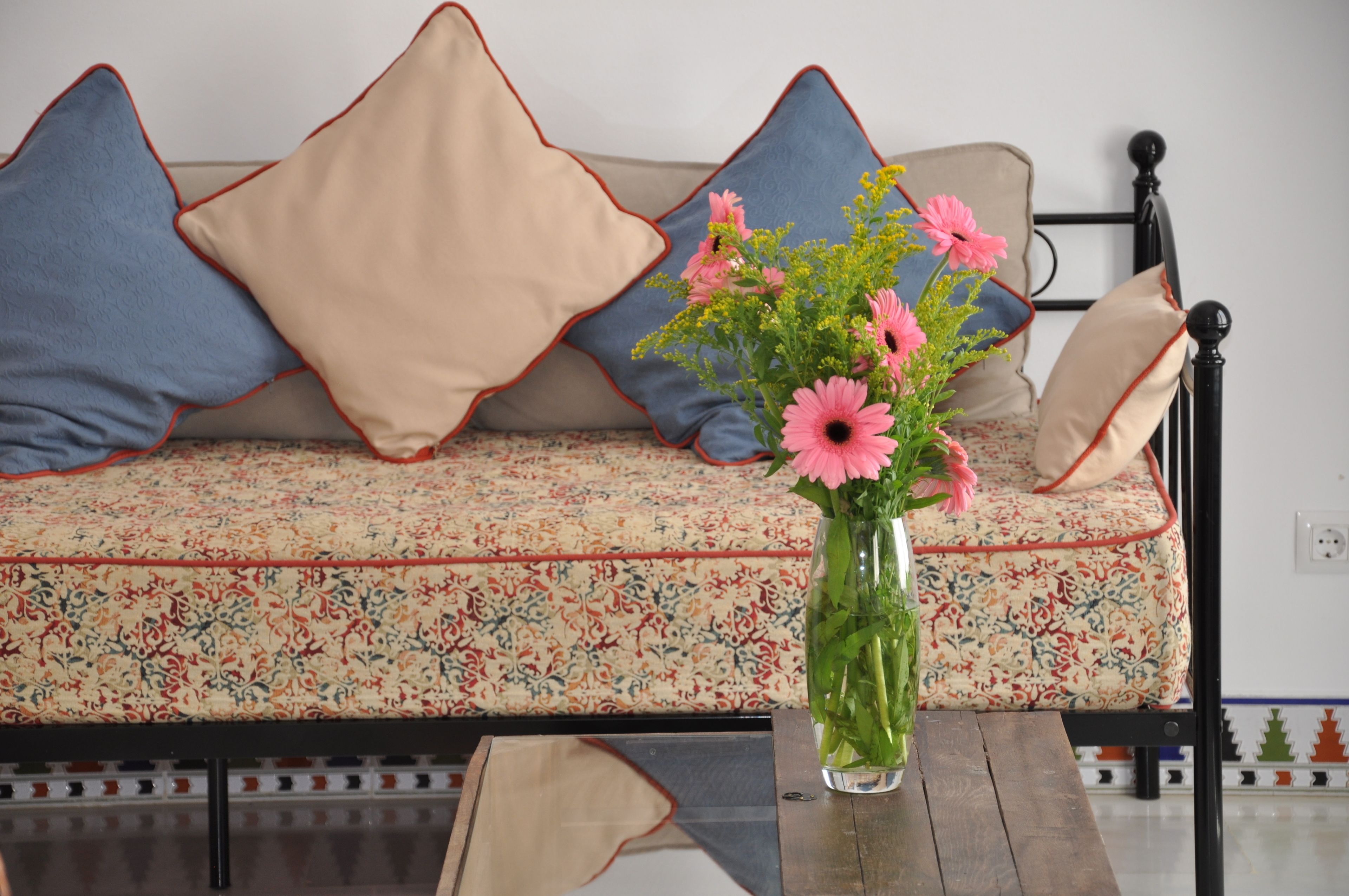 A sofa with patterned cushions and a vase with flowers on a table.
