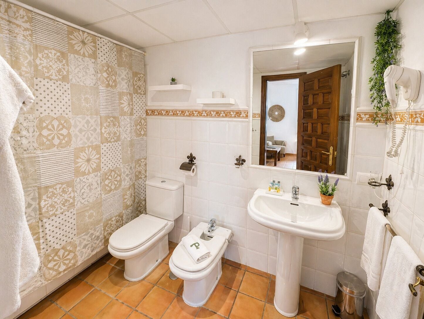 Une salle de bain avec deux toilettes, un lavabo, un miroir et un espace douche.