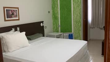 Une chambre à coucher avec un grand lit, une table de chevet, un mur d’accent de couleur verte et un tableau encadré accroché au mur.
