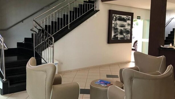 Un vestíbulo con una escalera, dos sillones, una mesita de centro y un cuadro enmarcado en la pared.