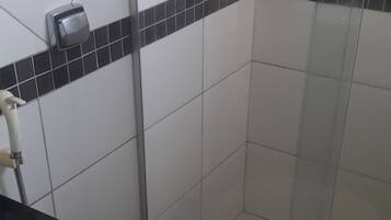 Casa de banho com sanita branca, cabine de duche e lavatório preto.