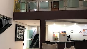 Un vestíbulo con piso de cuadros, una escalera y un mostrador de recepción.