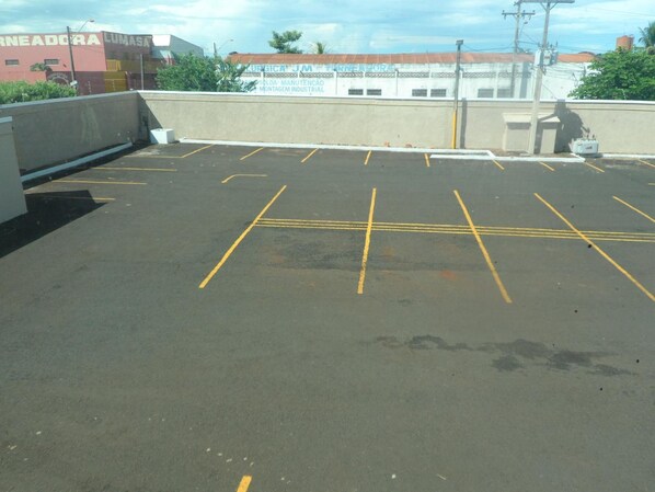 Un aparcamiento en la azotea con plazas delimitadas y vistas a edificios al fondo.