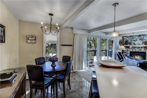 Enjoy dining and relaxation in this inviting space with a fireplace, large windows, and a chandelier.