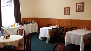 Een restaurant met houten lambrisering, witte tafellinnen en lijstwerken aan de muren.