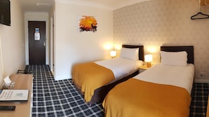 A hotel room with two beds, check-in desk, and a hallway leading to the door. - Star Hotel (Montrose)