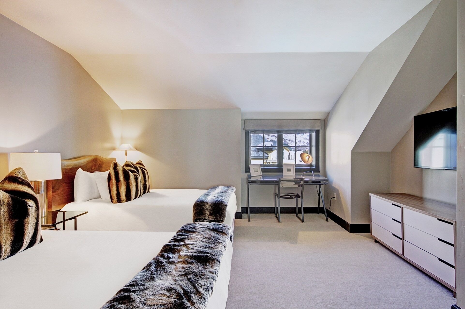 A modern bedroom with a large bed, a desk, and a TV.