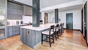 Una cocina moderna con una isla central, taburetes de bar y un área de comedor con sillas.