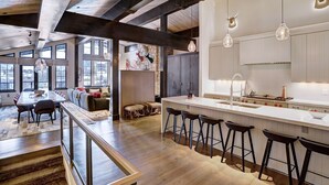 Une cuisine moderne dotée d’un îlot central, de tabourets de bar et d’un coin repas avec une longue table et des chaises.