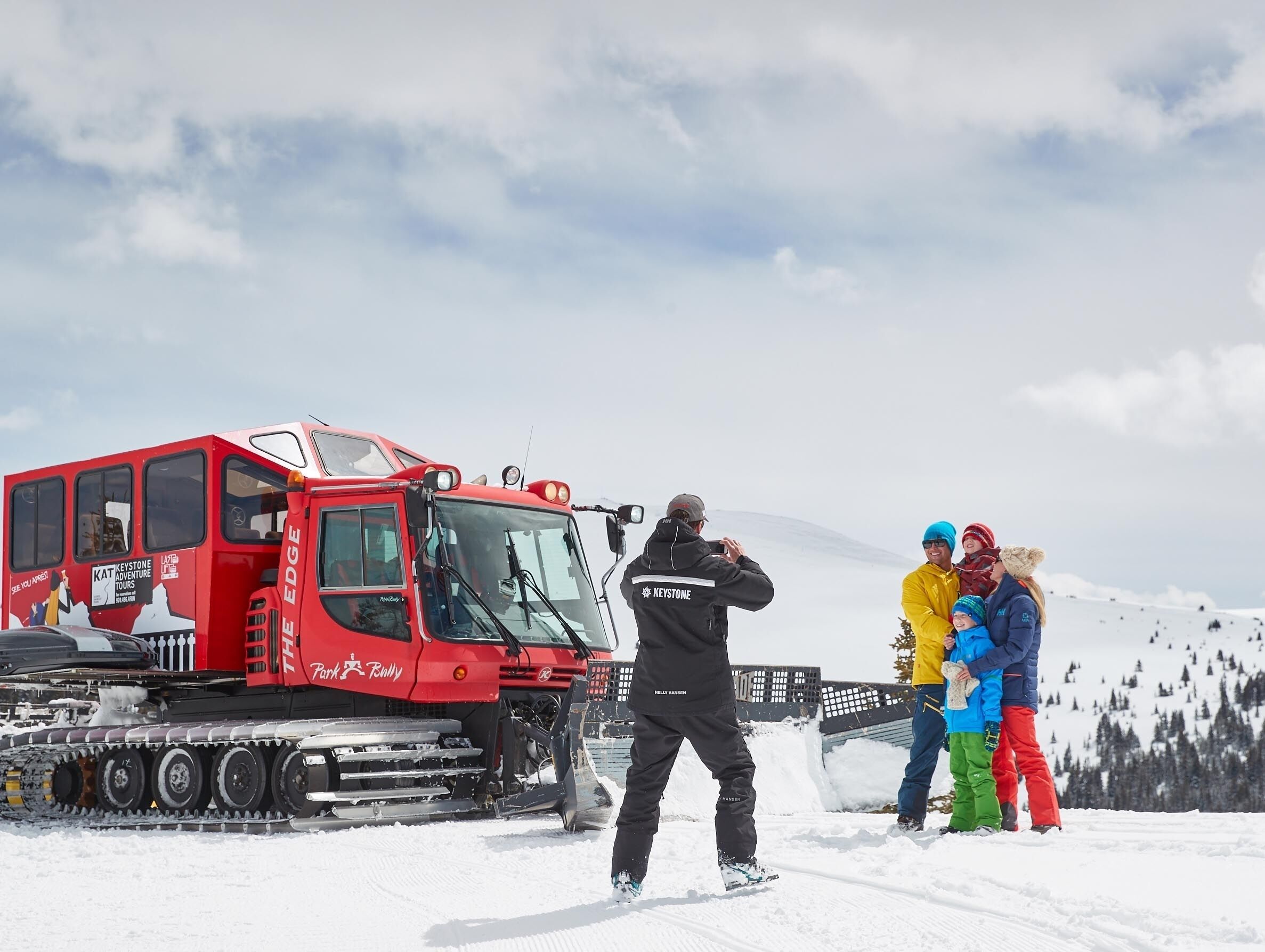 Vehículo rojo para nieve con la marca 'Keystone Adventure Tours' estacionado sobre nieve.